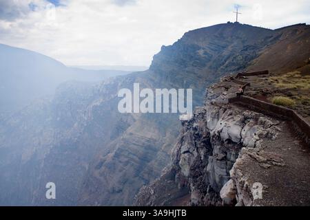 Januar 2007 - Masaya, Masaya , NICARAGUA - Masaya ist der aktivste Vulkan der Region. Die Spanier beschrieb den Vulkan erstmals 1524. Seitdem ist Masaya mindestens 19 Mal ausgebrochen. Die letzte Eruption fand 1993 statt. Masaya ist ein ungewöhnlicher basaltischer Vulkan, weil er explosive Eruptionen hatte. Die Eruption im Jahr 4550 v. Chr. war eine der größten der Erde in den letzten 10.000 Jahren. Im Bild: Ein Tourist sitzt an der Mauer vor dem Aussichtspunkt für den Vulkan Masaya und Dampf und Gase werden aus dem Vulkan im Masaya Volcano National Park in der Nähe von Masaya ausgestoßen. Stockfoto