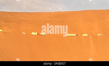 Trucks, die auf der Straße fahren, fahren durch sandige Berge oder Dünen, Pan American Highway in der Nähe von Lima, Peru Stockfoto
