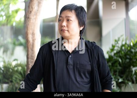 In einer eleganten Innenumgebung zeigt ein asiatischer Mann im mittleren Alter sein modisches Können, indem er ein elegantes schwarzes Poloshirt und eine schwarze Strickjacke trägt Stockfoto