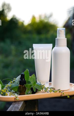 Weiße handgemachte Kosmetikflaschen Vorlage Mockup Hautpflege Kräuter Alternative Insektenschutz draußen im Sommer. Versuche, Mücken und Fliegen mit organischen Inhaltsstoffen Minzextraktöl zu töten. Prophylaxe-Desinfektion gegen Mückenstich an sonnigen Tagen. Stockfoto