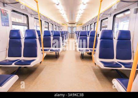 Ein Zugwagen mit blauen Sitzen und einem gelben Schild an der Wand. Der Zug ist leer. Auf dem gelben Schild steht „Rauchen verboten“. Stockfoto