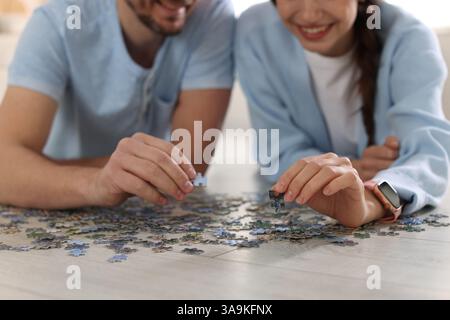 Paare lösen zusammen Puzzle auf dem Boden drinnen, Nahaufnahme Stockfoto