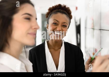 Fröhlich schöne junge afrikanische Geschäftsfrau, die am Whiteboard steht Stockfoto