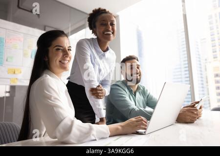 Fröhliche, vielfältige junge Bürofreunde genießen Teamarbeit im Tagungsraum Stockfoto