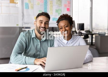 Glückliche junge Geschäftspartner, die sich im Büro für ein Porträt ausgeben Stockfoto
