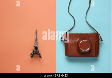Retro-Bild mit Retro-Kamera und eiffelturmfigur auf farbigem Papierhintergrund. Stockfoto