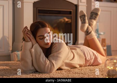 Frau in warmen Socken, die sich zu Hause am Kamin ausruhen Stockfoto