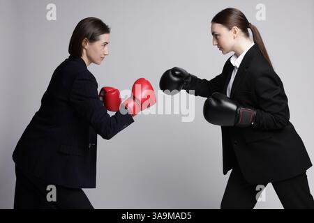 Wettbewerb. Geschäftsfrauen im Handschuhboxen auf grauem Hintergrund Stockfoto