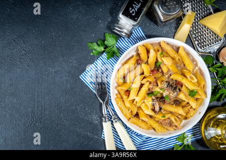 Italienisches mediterranes Mittagskonzept. Penne mit cremiger Kohlensäurehalzsauce. Auf einem Tisch mit weißen Fliesen, mit Gewürzen für das Abendessen, Platz zum Kopieren Stockfoto