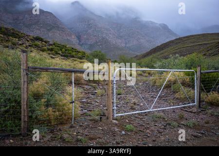 Farm Gate und die Swartberg Mountains bei wildem und windigem bewölktem Wetter. In der Nähe von Klaarstroom und de Rust. Westkap. Südafrika Stockfoto