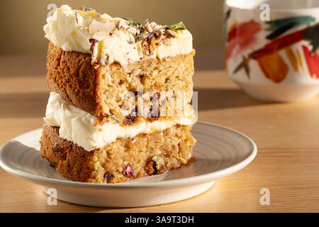 Ein frisch gebackenes Stück veganer Karotten- und Zucchini-Kuchen. Der Kuchen wird auf einem Café-Tisch mit einer frischen Tasse schwarzen Kaffee serviert Stockfoto