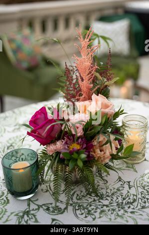 Elegantes, florales Herzstück mit Kerzen bei einer romantischen Hochzeit im Freien Stockfoto
