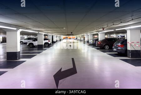 The Haag, Niederlande - 24. August 2024: Geräumige Tiefgarage mit mehreren Autos, die auf beiden Seiten geparkt sind und von weißen Säulen und Dire gekennzeichnet sind Stockfoto