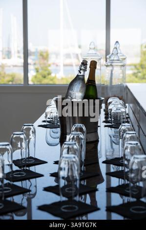 Champagner- und Wasserflaschen in Eiskübel an einer Bar mit Gläsern Stockfoto