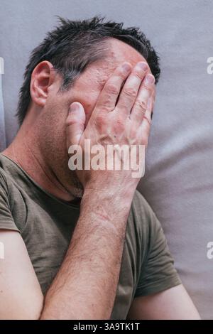 Hochwinkelansicht von reifem erwachsenen Mann, der auf dem Schlafsofa weint, selektiver Fokus Stockfoto