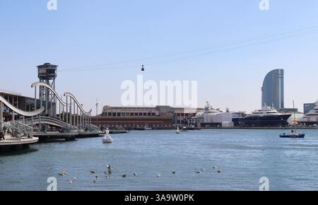 Rambla de Mar Fußgängerbrücke in Barcelona mit Touristen, Möwen und Seilbahn mit Blick auf Port Vell Stockfoto