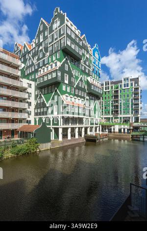 Farbenfrohes Inntel Hotel in Zaandam, übereinander gestapelte traditionelle Zaanse Häuser in Grün und Blau und Kanal davor. Stockfoto