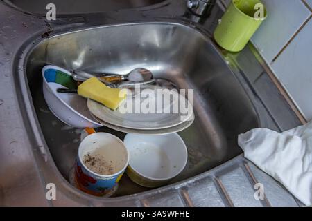 Geschirr reinigen. Schmutzige Tassen, Teller, Messer, Gabeln und Löffel werden im Waschbecken der Campingküche gewaschen. Waschutensilien. Metallbearbeitung Stockfoto