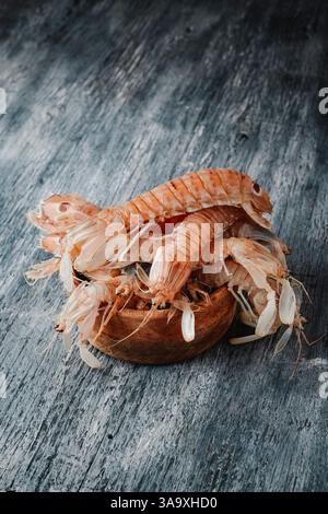 Einige spanische galeras, Squilla Mantis, eine Art Mantis Garnelen, auf einer Holzschale auf einem grauen rustikalen Holztisch Stockfoto