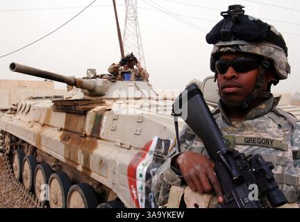 10. März 2006; Halasba, IRAK; PFC der US-Armee Frederick Gregory behält die Perimetersicherheit bei, während ein irakischer Armeesoldat die Gegend von seinem gepanzerten Fahrzeug aus nach einem improvisierten Bombenangriff auf ihren Konvoi in Halasba, Irak, durchsucht. Gregory wird dem 1. Bataillon, 66. Panzerregiment, und der irakische Soldat der 9. Mechanischen Division zugeordnet. Obligatorischer Ausweis: Foto von Michael Larson/US Navy/ZUMA Press. (©) Copyright 2006 by US Navy Stockfoto