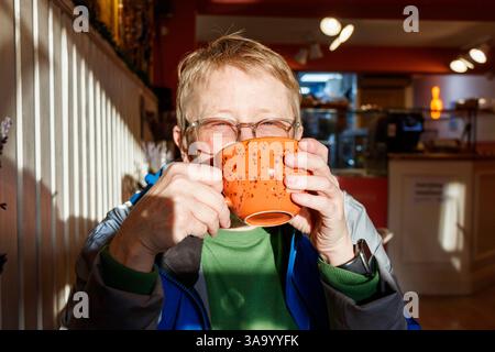 Eine Frau, die aus einem großen Becher in einem Café trinkt, London, Großbritannien Stockfoto