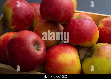 Nahaufnahme von frischen kleinen roten Bio-Äpfeln in einer Holzkiste Stockfoto
