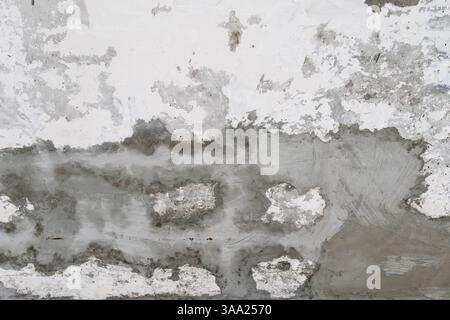 Das Bild zeigt eine Nahansicht einer alten Wand mit abblätternder Farbe und sichtbaren Texturen. Die Oberfläche zeigt Anzeichen von Verwitterung und Verfall, was einen anbietet Stockfoto