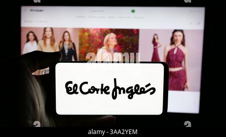 In dieser Abbildung hält eine Person ein Handy mit dem Logo des spanischen Einzelhandelsunternehmens El Corte Ingles S.A. auf dem Bildschirm vor der Webseite. Stockfoto