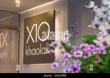Thailand, Khao Lak 11 02 2025: Das Zeichen des Namens des thailändischen Hotels X10 in Kaolak am Eingang auf einem Hintergrund von Blumen Stockfoto