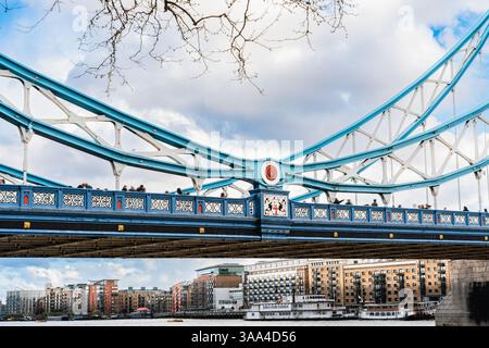 Die Menschen laufen entlang der Tower Bridge über der Themse mit sichtbaren Stahlkonstruktionen und Flussbooten darunter Stockfoto