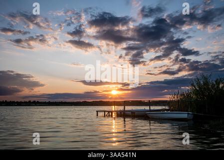 Zwei Fischerboote neben einem hölzernen Pier bei Sonnenuntergang auf dem Paljuvi-See in Serbien. Stockfoto