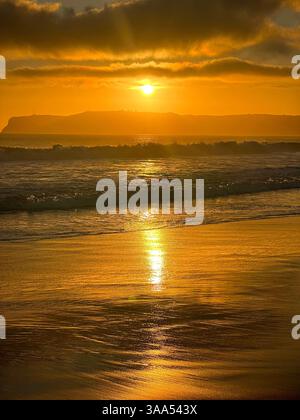Wunderschöner Sonnenuntergang an der Küste Kaliforniens am Strand, mit leuchtenden Farben, die den Himmel erleuchten und sich auf dem Meer spiegeln. Stockfoto