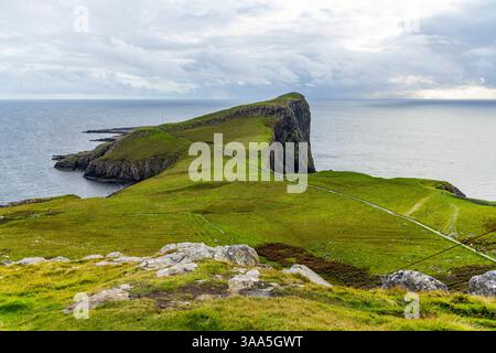Der Neist Point bei Sonnenuntergang ist ein atemberaubender Anblick – sein Leuchtturm steht vor dramatischen Klippen, unter denen Wellen krachen. Ein Regenbogen überwölbt den Ozean Stockfoto