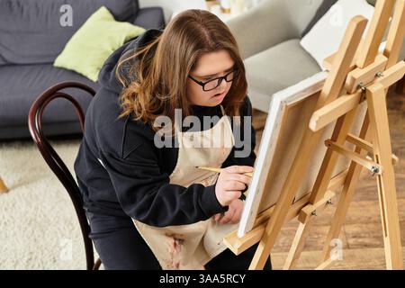 Eine junge Frau mit Down-Syndrom zeigt ihre Kreativität und Selbstvertrauen durch Kunst zu Hause. Stockfoto