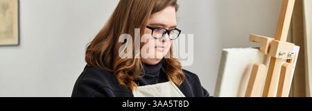 Selbstbewusste junge Frau mit Down-Syndrom zeigt ihr Maltalent in einem gemütlichen Zuhause. Stockfoto