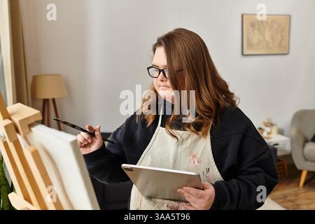 Eine junge Frau mit Down-Syndrom zeigt ihre Kreativität beim Malen zu Hause. Stockfoto