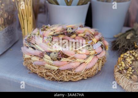 Osterdekor, Kranz, Nest aus getrockneten Kräutern und Ohren, dekoriert mit farbigen und Wachteleiern. Stockfoto