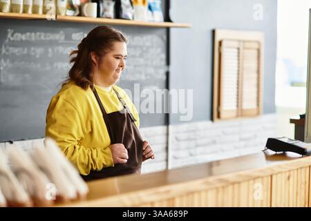 Eine junge Frau mit Down-Syndrom zeigt Selbstvertrauen und Wärme in einem geschäftigen Café. Stockfoto