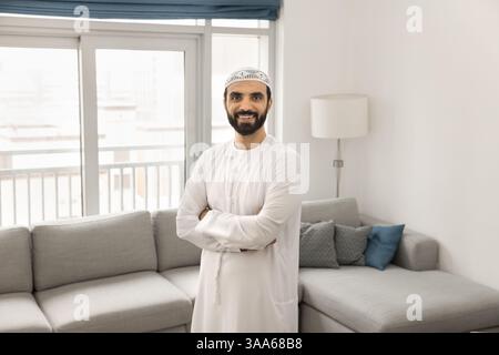 Ein arabischer Mann in weißer Dschungasha, der im Wohnzimmer posiert Stockfoto
