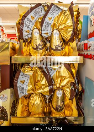 Italien - 30. März 2025: Ferrero Rocher Ostereier aus dunkler Haselnuss mit Schaukelschokolade überraschend in goldener Pappe zum Verkauf Stockfoto