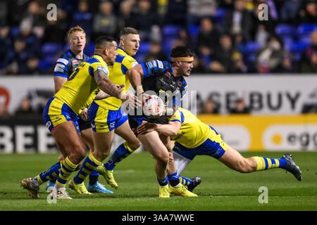 WARRINGTON, ENGLAND - 28. MÄRZ 2025: James Bentley von Leeds Rhinos wird während des Betfred Super League Roun von Ben Currie von Warrington Wolves bekämpft Stockfoto