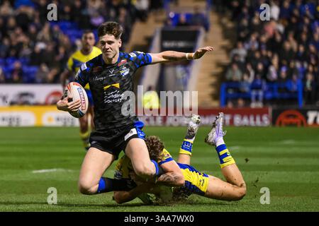 WARRINGTON, ENGLAND - 28. MÄRZ 2025: Riley Lumb von Leeds Rhinos wird während der Betfred Super League Runde von Arron Lindop von Warrington Wolves bekämpft Stockfoto