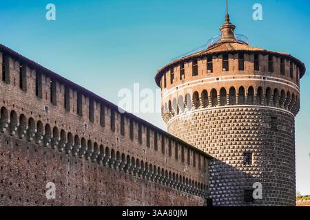 Ein großer Uhrenturm mit einer weißen und roten Flagge oben in Mailand Italien. Die Uhr befindet sich auf dem Turm und ist von weitem sichtbar. Der Turm ist s Stockfoto