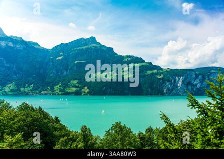 Ein wunderschöner See mit einem Berg im Hintergrund in den Schweizer Alpen. Das Wasser ist blau und es gibt mehrere Segelboote auf dem See Stockfoto