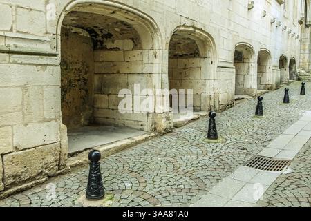 Eine Reihe von Straßenpfosten aus schwarzem Metall stehen auf einer Kopfsteinpflasterstraße. Die Pfosten sind gleichmäßig verteilt und in einer Reihe platziert Stockfoto