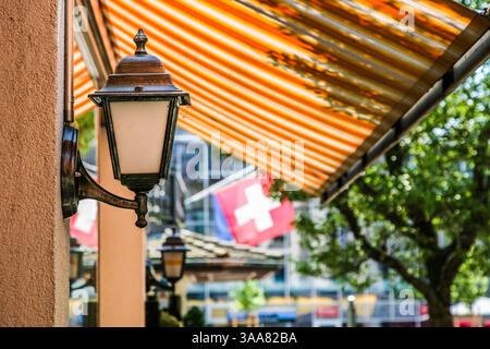 Eine Straße in Luzern Schweiz Licht hängt an einer Wand. Im Hintergrund befindet sich ein Flag. Die Flagge ist blau und weiß Stockfoto