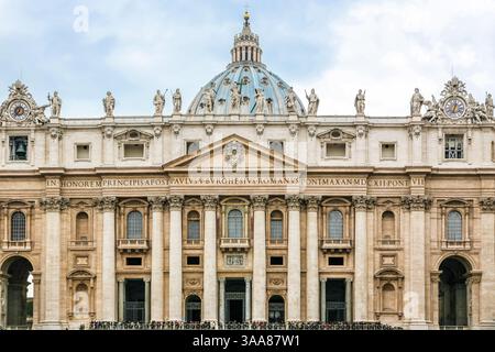 Ein großes Gebäude St. Peter Kirche des Vatikans in Italien mit einer blauen Kuppel und einem Kreuz auf der Spitze. Auf dem Gebäude befinden sich viele Statuen Stockfoto