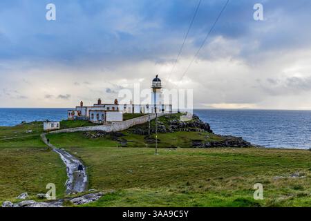 Der Neist Point bei Sonnenuntergang ist ein atemberaubender Anblick – sein Leuchtturm steht vor dramatischen Klippen, unter denen Wellen krachen. Ein Regenbogen überwölbt den Ozean Stockfoto