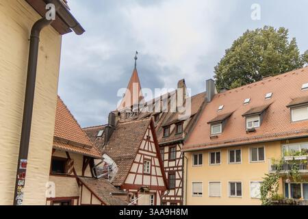 NÜRNBERG, DEUTSCHLAND. Malerische Fachwerkhäuser mit roten Ziegeldächern und Blumenkästen stehen auf dem Kopfsteinpflasterplatz in einer kleinen deutschen Stadt auf bewölktem Sum Stockfoto