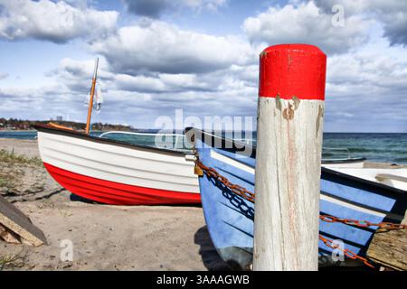 Ein rot-weißes Boot parkt am Sandstrand neben einem blauen Boot Ostsee in Deutschland. Das rote Boot befindet sich auf der linken Seite des blauen B Stockfoto